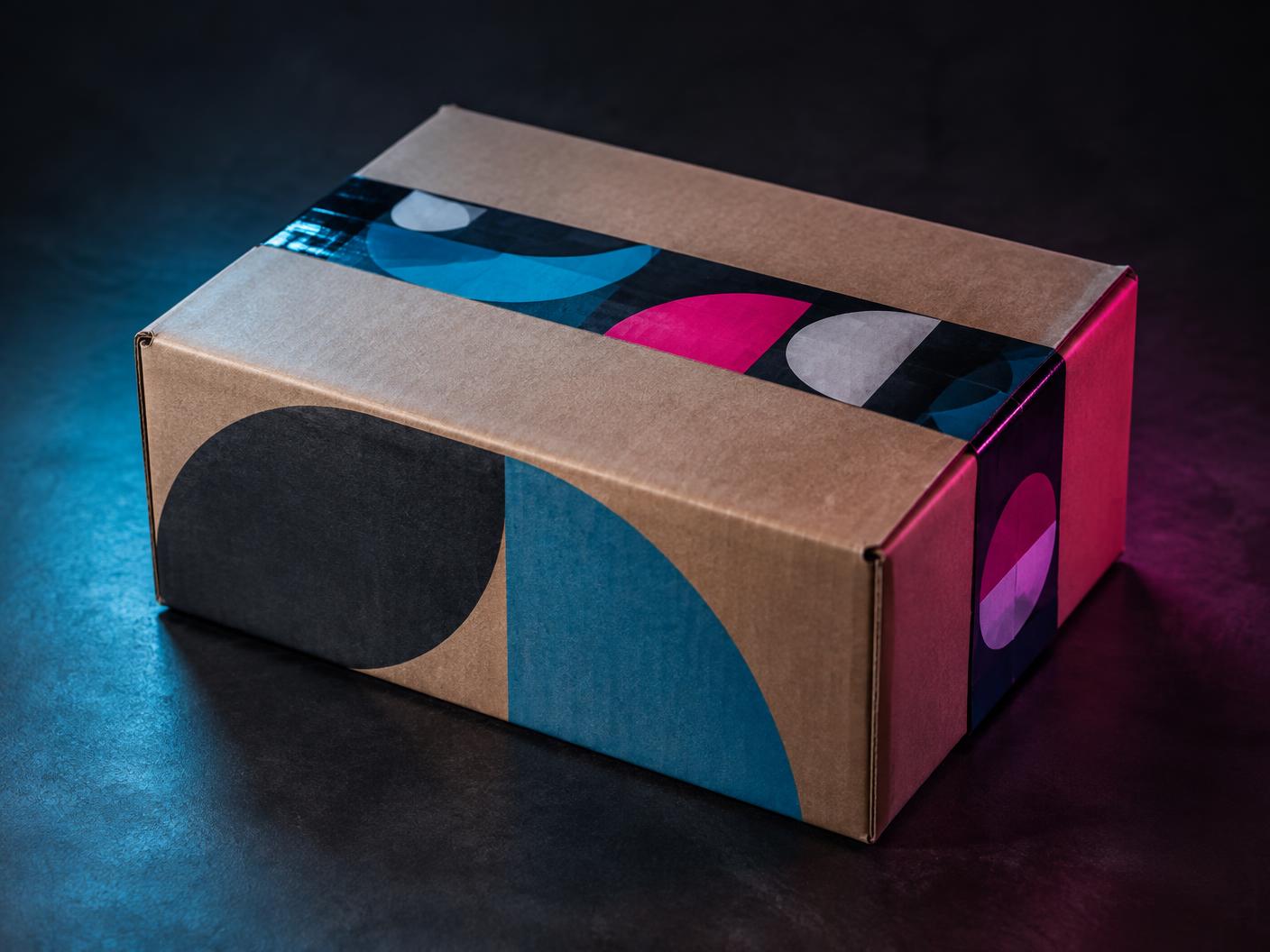 Caja de envío cerrada con cinta y zonas gráficas de marca en el exterior